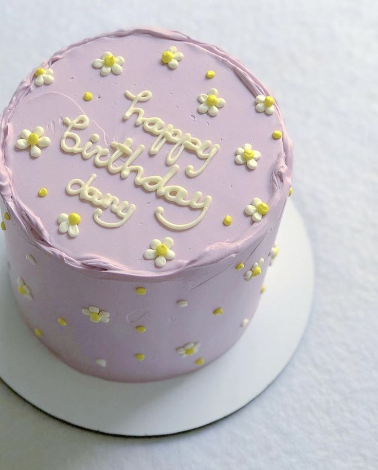 a pink birthday cake with white and yellow flowers on it