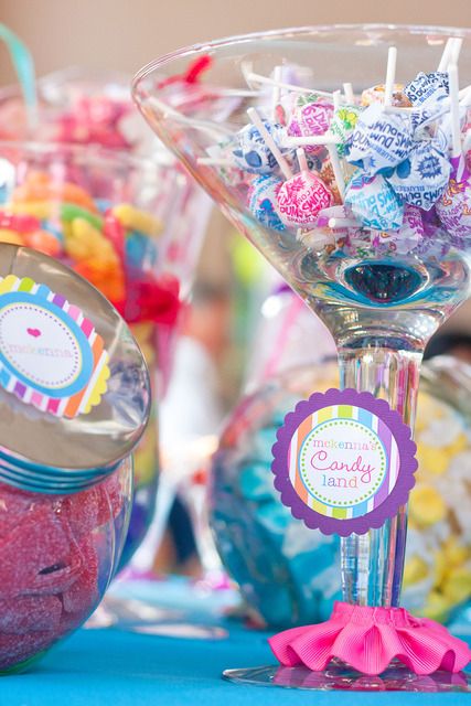 there are many candies in glass bowls on the table with candy sticks and lollipops