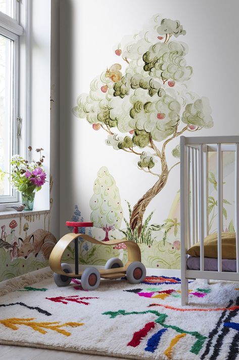 a child's room with a tree painted on the wall and a toy car