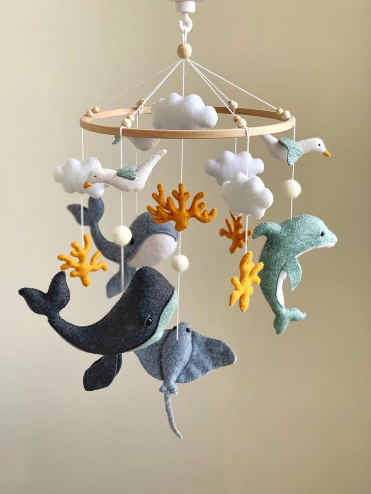 a baby mobile with sea animals hanging from it's sides and clouds in the background