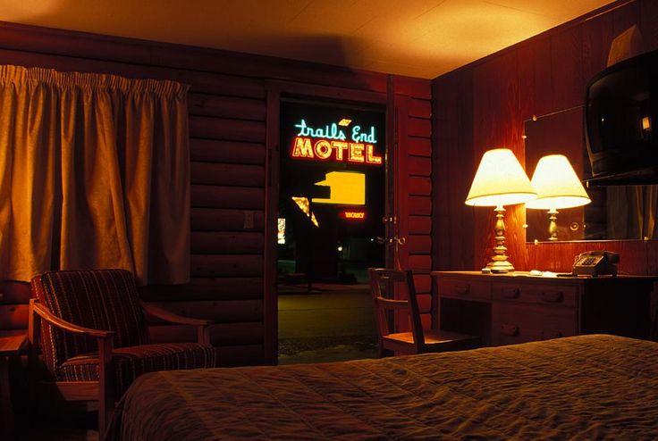 a hotel room with a bed and two lamps on the nightstands, in front of a large wooden paneled wall