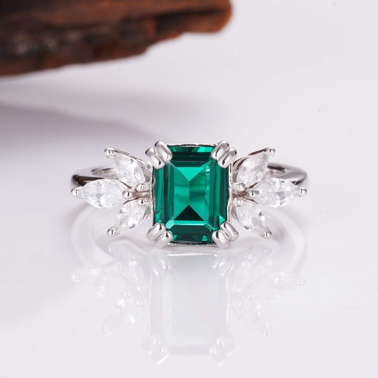 Few color schemes have a more sophisticated and luxurious feel than the iconic pairing between silver and emerald green – and this is a style we’ve captured in our stunning Ivy ring design. Simplistic yet beautiful, our Emerald ivy ring features a massive, 2.0-carat emerald as the main center, while six striking CZ crystals transform the look and create an unrivaled level of sophistication overall. ✦ DETAILS ✦✧ Handcrafted ✧ 2.0 Carat center stone✧ Emerald and cz crystals ✧ Sizes 3.75-11.25✧ Thi Elegant Emerald-cut Emerald Ring For Proposal, Elegant Emerald Cut Emerald Ring For Proposal, Fine Jewelry Rose Gold Emerald Ring, Elegant Emerald Cut Emerald Ring For Promise, Elegant Emerald Cut Emerald Promise Ring, Rose Gold Emerald Ring For May Birthstone, Elegant Emerald Rose Gold Rings, Elegant Rose Gold Ring With Emerald, Elegant Rose Gold Emerald Ring For May Birthstone