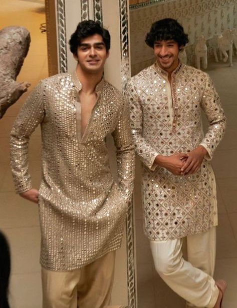 two men standing next to each other in front of a mirror wearing gold and white outfits