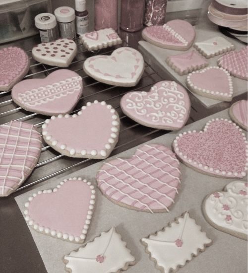 some heart shaped cookies on a rack in a kitchen with pink and white icing