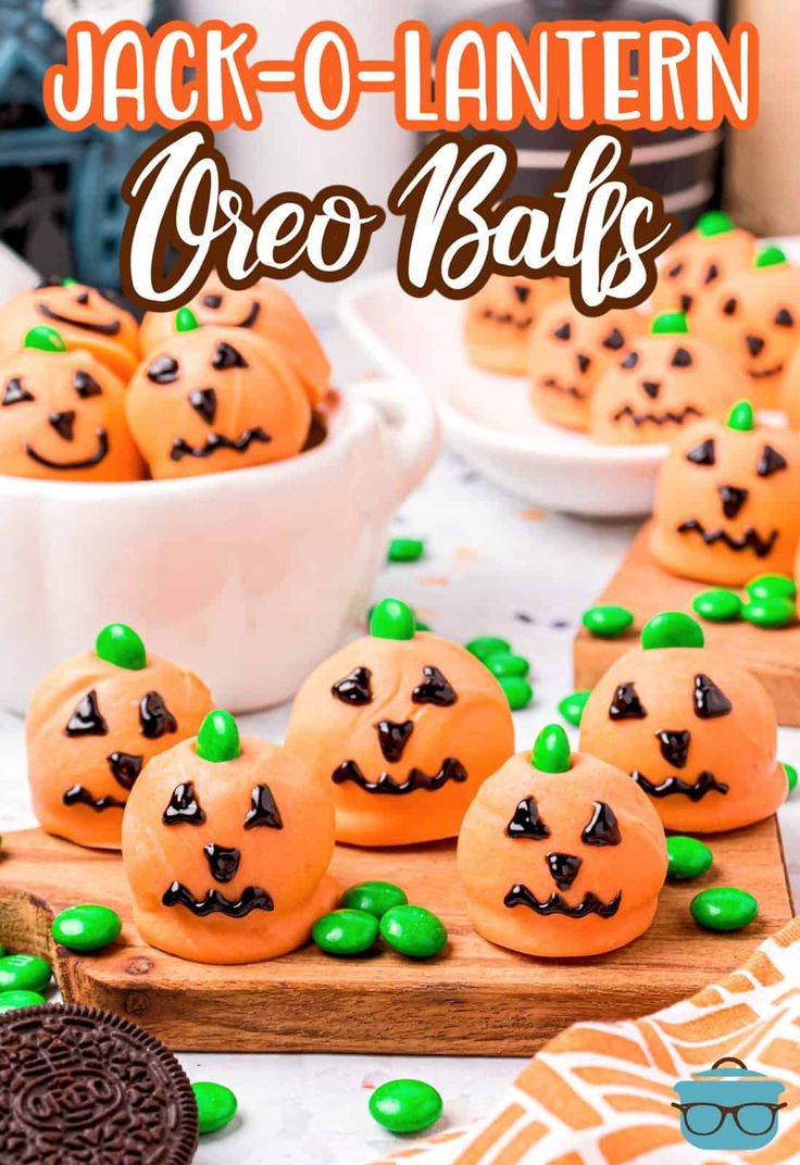 jack o lantern oreo balls on a wooden board with green candies around them