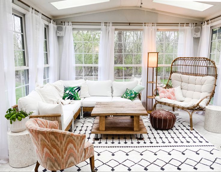 a living room filled with lots of furniture next to two large windows and a rug on the floor