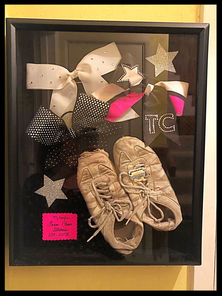 a pair of tennis shoes are on display in a shadow box with ribbons and bows