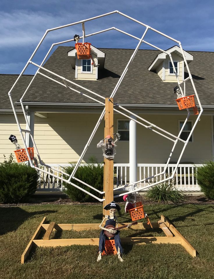 a man sitting on top of a wooden structure in front of a house with orange boxes attached to it