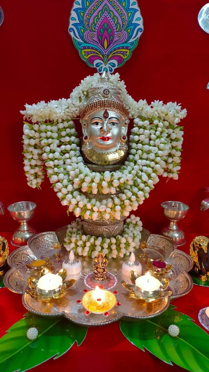 there is a statue with many candles on the table and decorations around it in front of a red wall