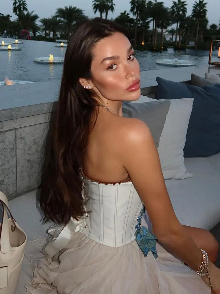 a beautiful woman sitting on top of a couch next to a white bag and purse