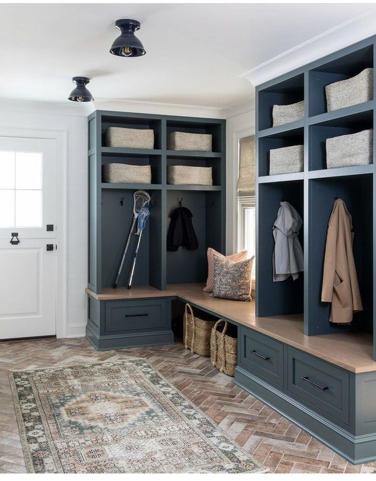 a mud room filled with lots of blue cabinets and shelves next to a rug on the floor