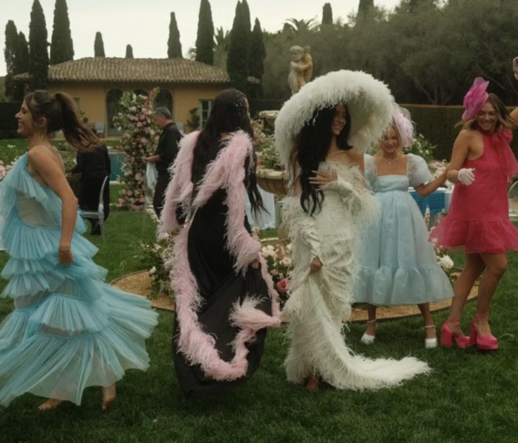 several women dressed up in costumes standing on the grass