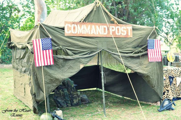 a tent with two flags on it and some other items in the grass next to it