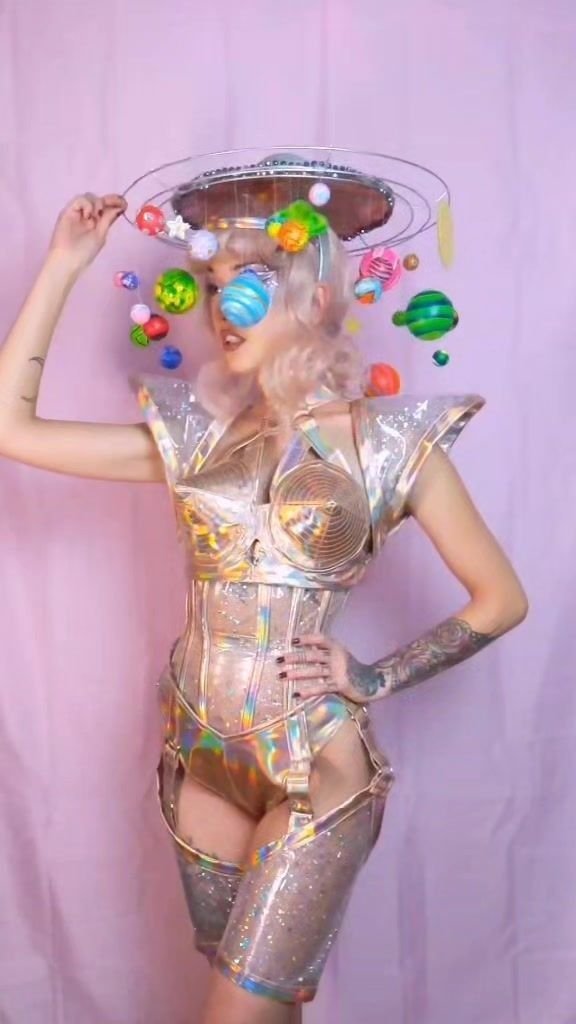 a woman in a silver bodysuit with lots of candies on her head and hands