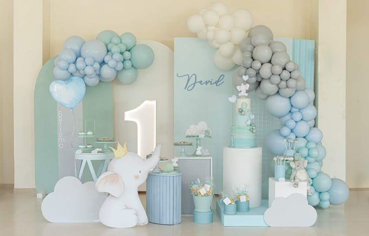 a baby's first birthday party with balloons, cake and other items in pastel colors