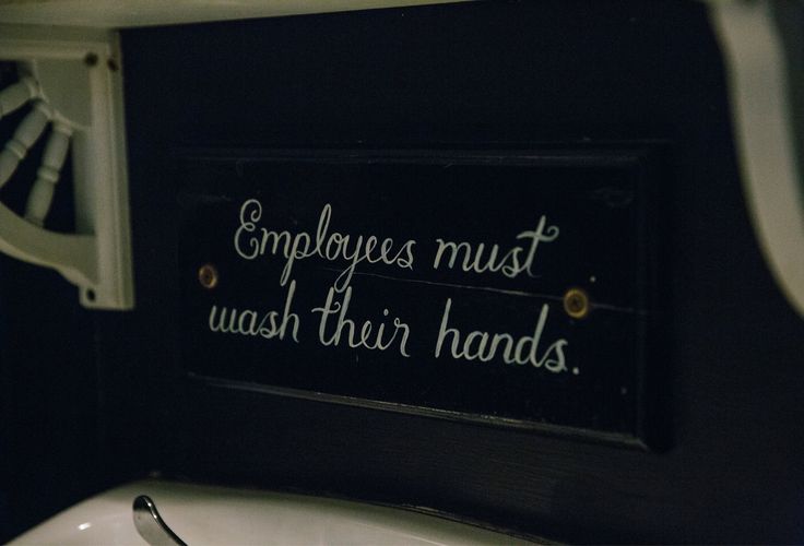 a sign that says employees must wash their hands next to a sink in a bathroom