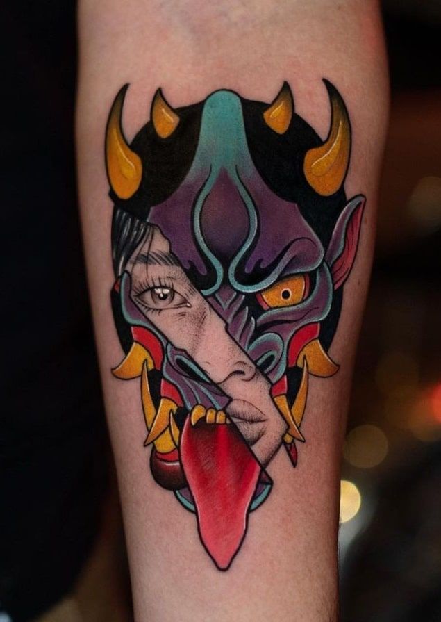 a tattoo on the arm of a man with an evil mask and tongue sticking out