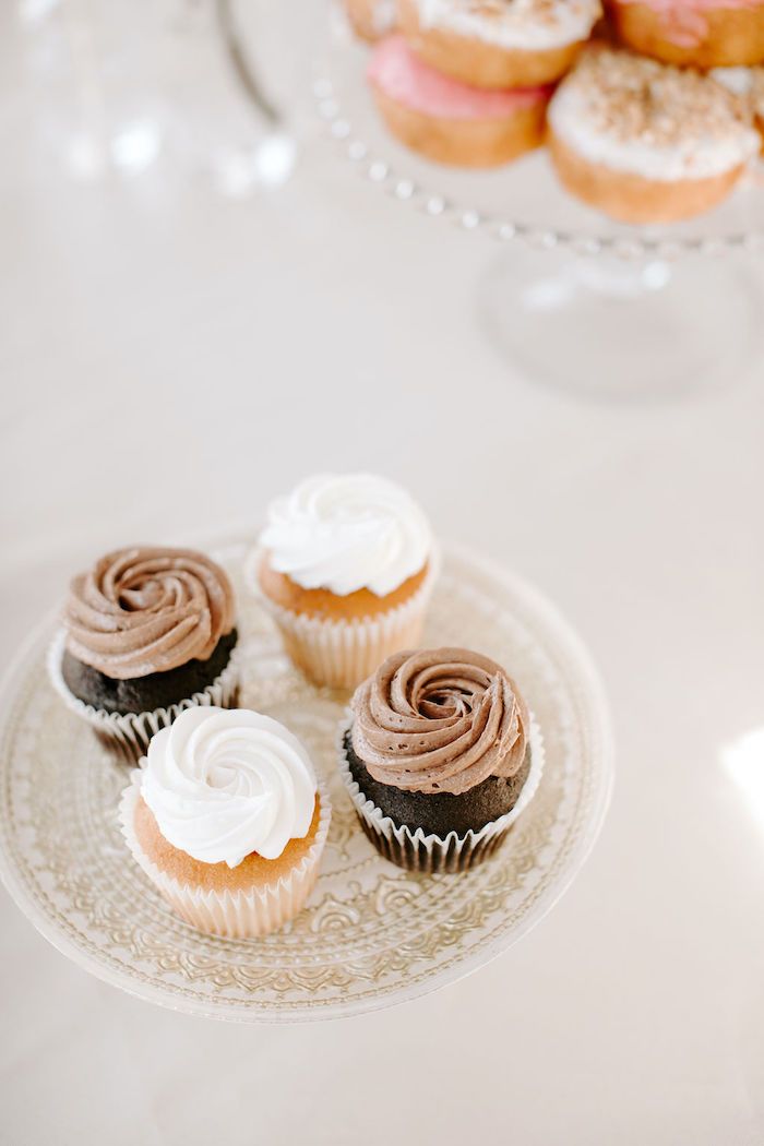 three cupcakes on a plate with frosting and sprinkles in the background