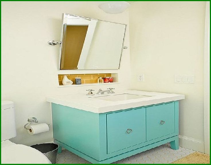 a white toilet sitting next to a bathroom sink under a mirror above a blue cabinet