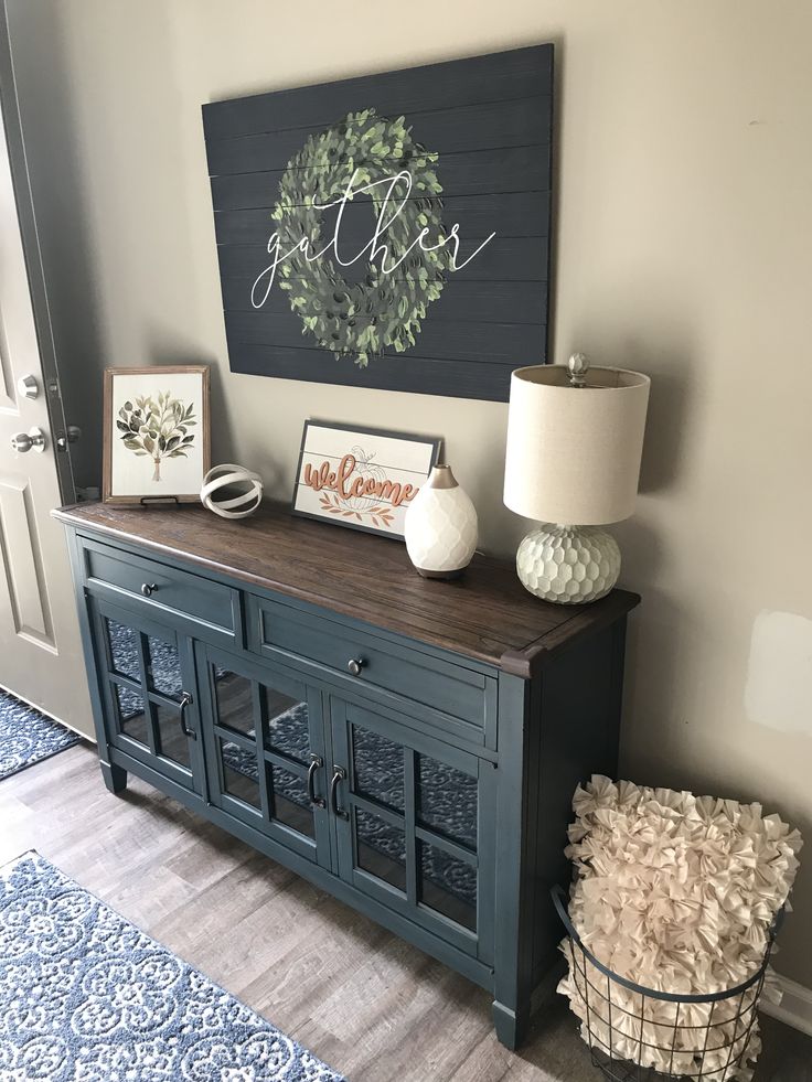 a living room with a blue cabinet and white vases on the sideboard next to it