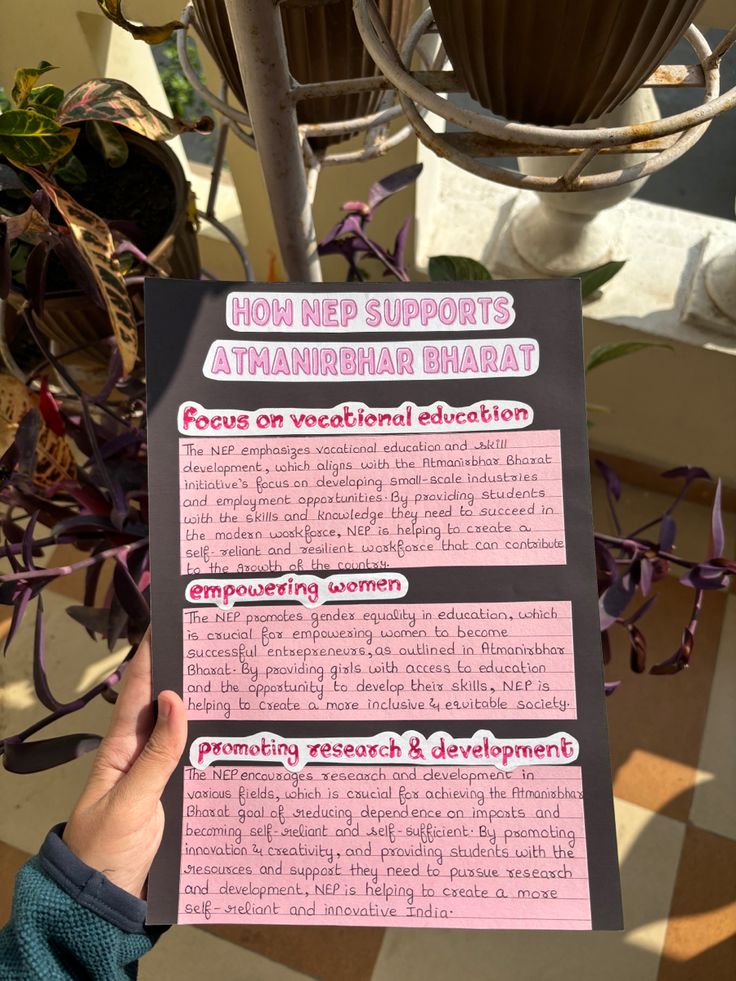 a person holding up a pink and black paper with information about plant life on it