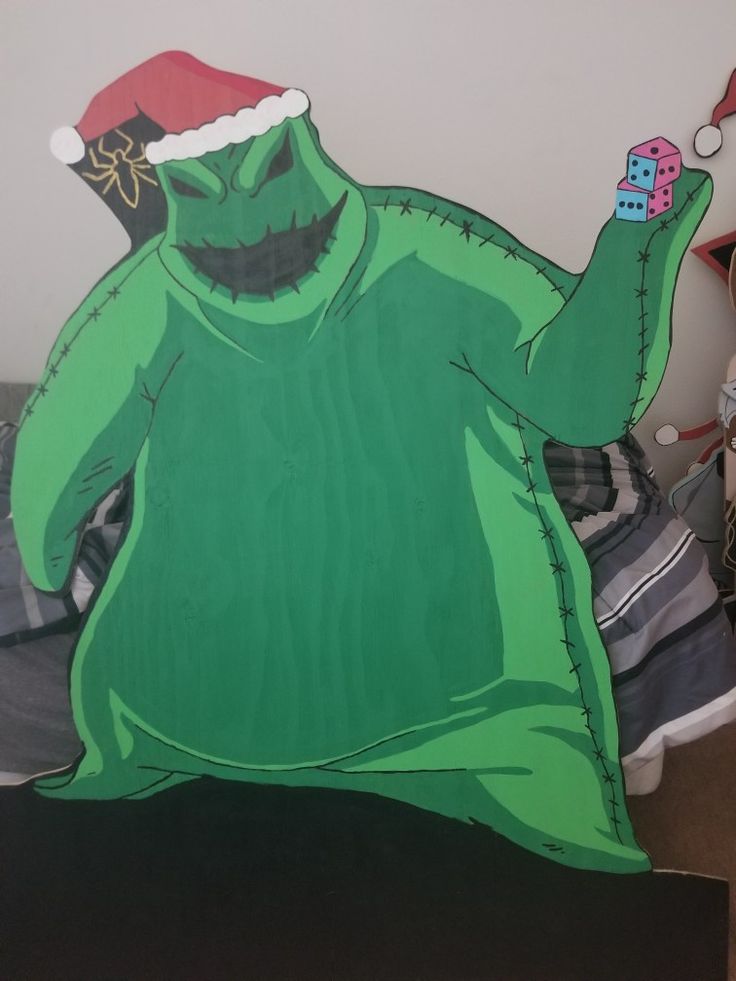 a cardboard cutout of a green monster wearing a santa hat and holding a cell phone