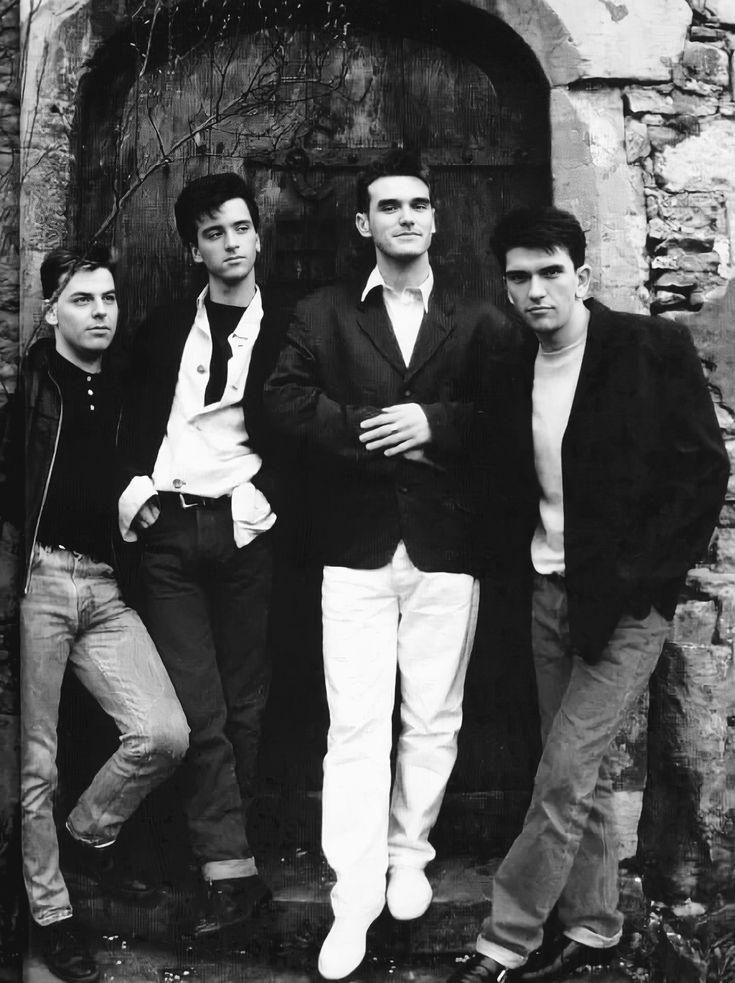 four young men are posing in front of an old door, black and white photo