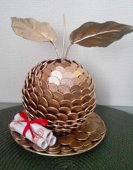 a gold plate with some coins in it and a plant growing out of the top