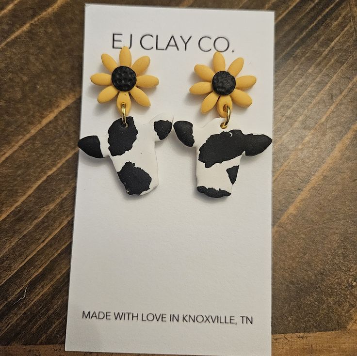 the earrings are made with black and white cow's head, sunflowers on each ear