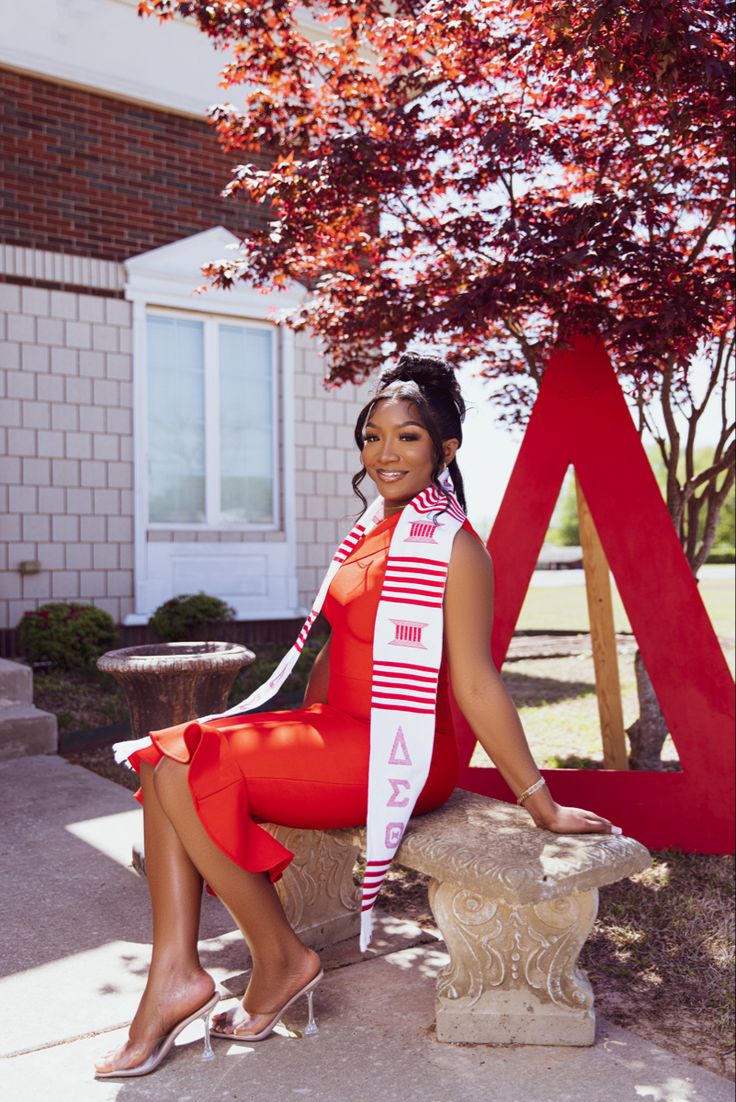 a woman in a red dress is sitting on a bench and posing for the camera