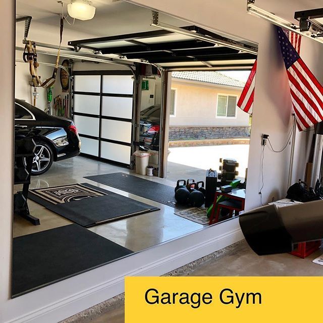 garage gym with an american flag hanging from the ceiling and two cars parked in the garage