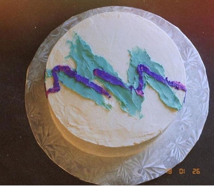 a white cake with blue and purple frosting on it's side sitting on a glass plate