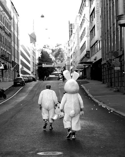 two stuffed animals walking down a street next to tall buildings with the words dream it plant it do it