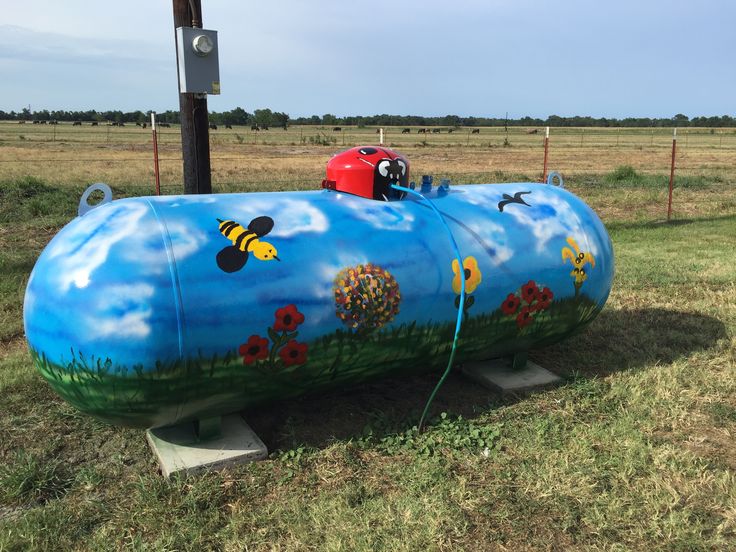 a large blue tank sitting on top of a lush green field next to a wooden pole