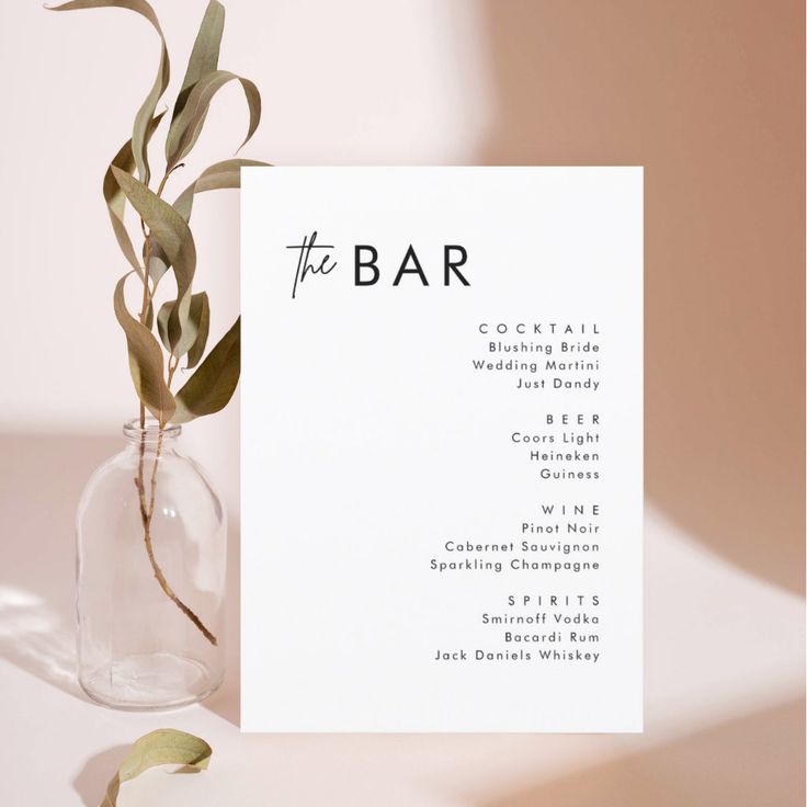 the bar menu is displayed in a clear glass vase with greenery on its side