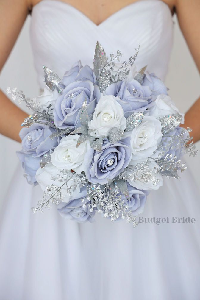 a bride holding a bouquet of blue and white flowers on her wedding day with silver leaves