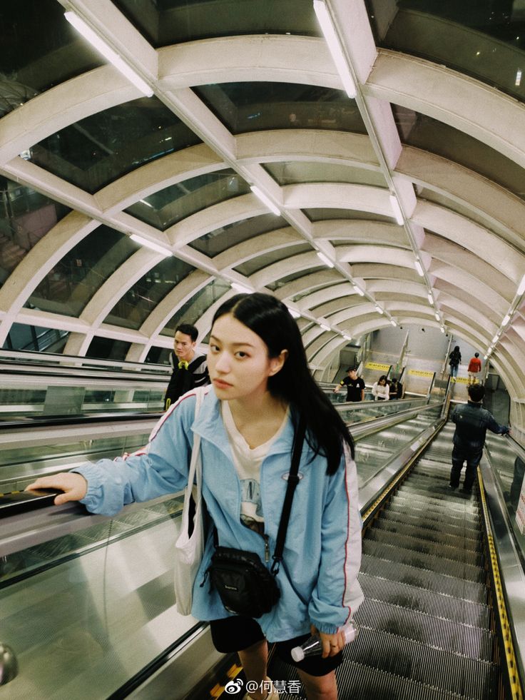 a woman is riding an escalator at the station with her hand on the railing