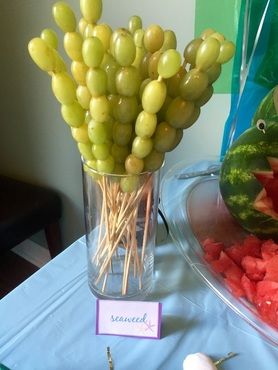 watermelon, grapes and other fruits are displayed in vases on a table