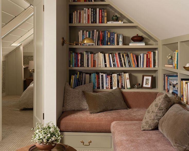 a living room filled with lots of books on top of a book shelf next to a couch