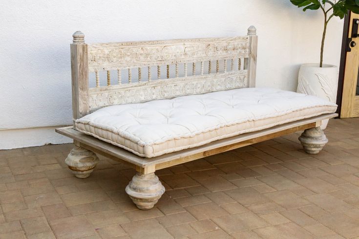 a white bench sitting on top of a tiled floor next to a potted plant