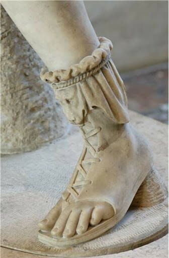 a close up of a person's foot wearing roman sandals