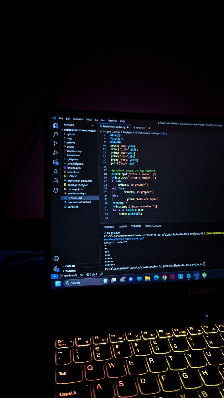 an open laptop computer sitting on top of a dark table next to a neon lit keyboard