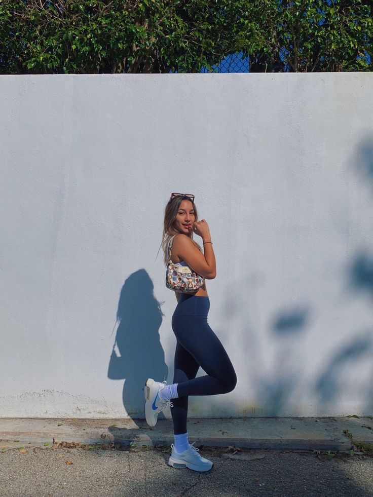 a woman is standing in front of a white wall and talking on her cell phone