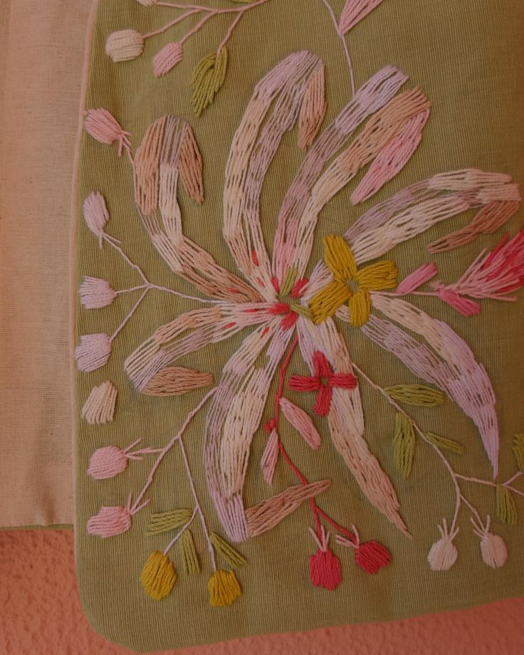 a green bag with pink and yellow flowers on the inside is sitting on a bed