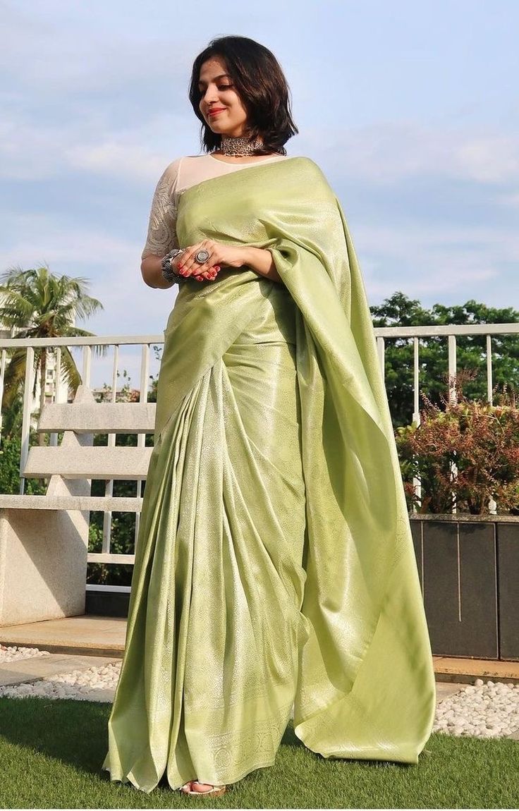 a woman in a green sari is standing on the grass with her arms crossed