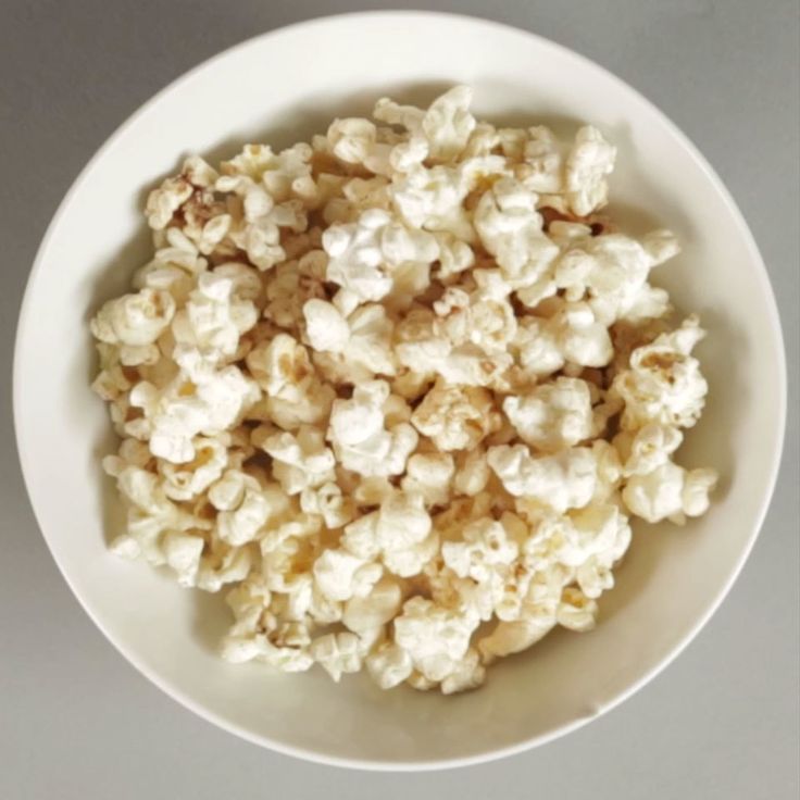 a white bowl filled with popcorn on top of a table