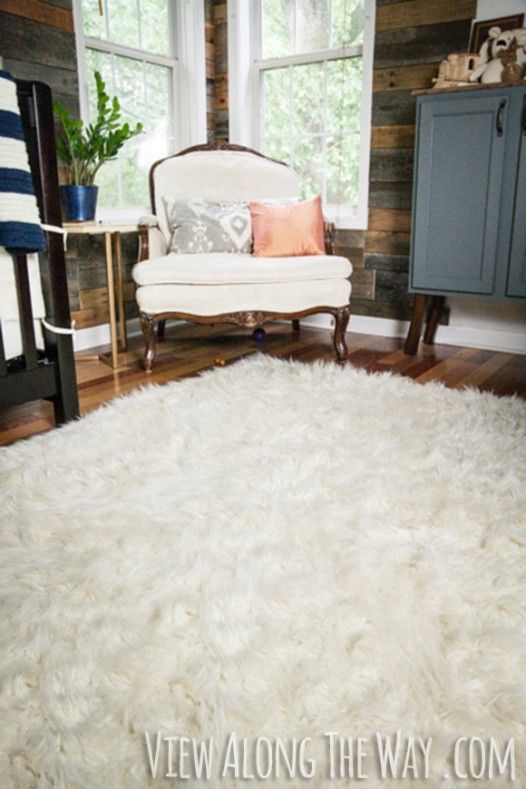 a living room with a white rug on the floor and a chair in front of a window