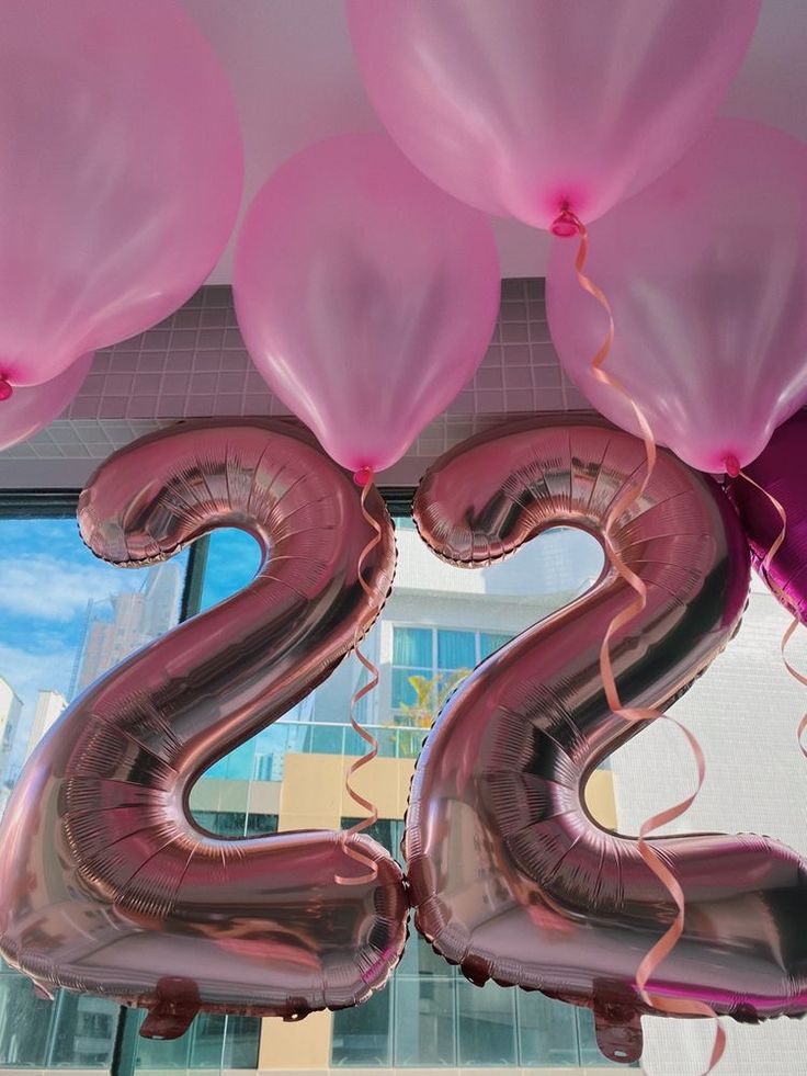 the number twenty two made out of pink and silver balloons in front of a building