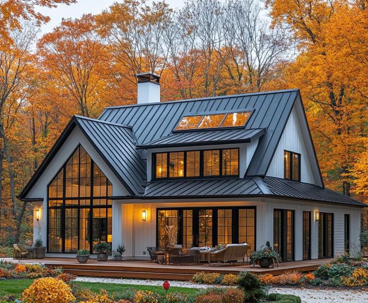 a house in the woods with lots of trees and flowers around it, surrounded by fall foliage