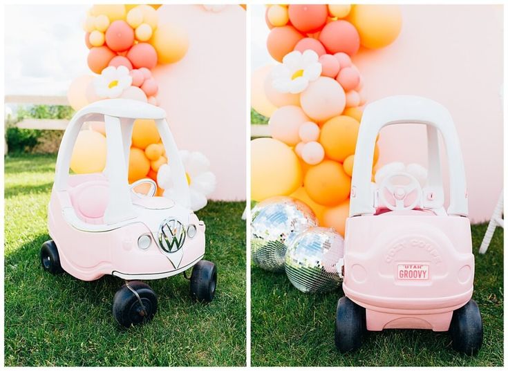 a pink toy car sitting on top of a lush green field next to a balloon wall